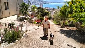 My dog and I walking up a hill with views of Saranda, Albania in the background